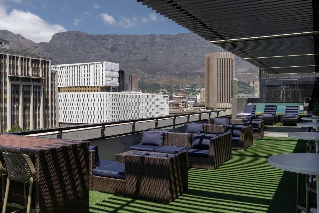 Radisson Hotel Cape Town Foreshore في كيب تاون: شرفة مع كراسي وطاولات على مبنى