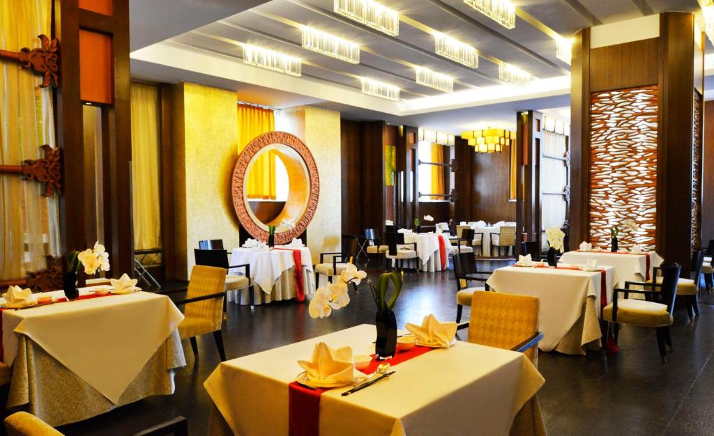 a restaurant with white tables and chairs and a mirror at Kempinski Hotel Dalian in Dalian