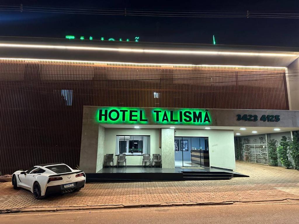 um carro branco estacionado em frente a um edifício de hotel em Hotel Talismã em Rondonópolis