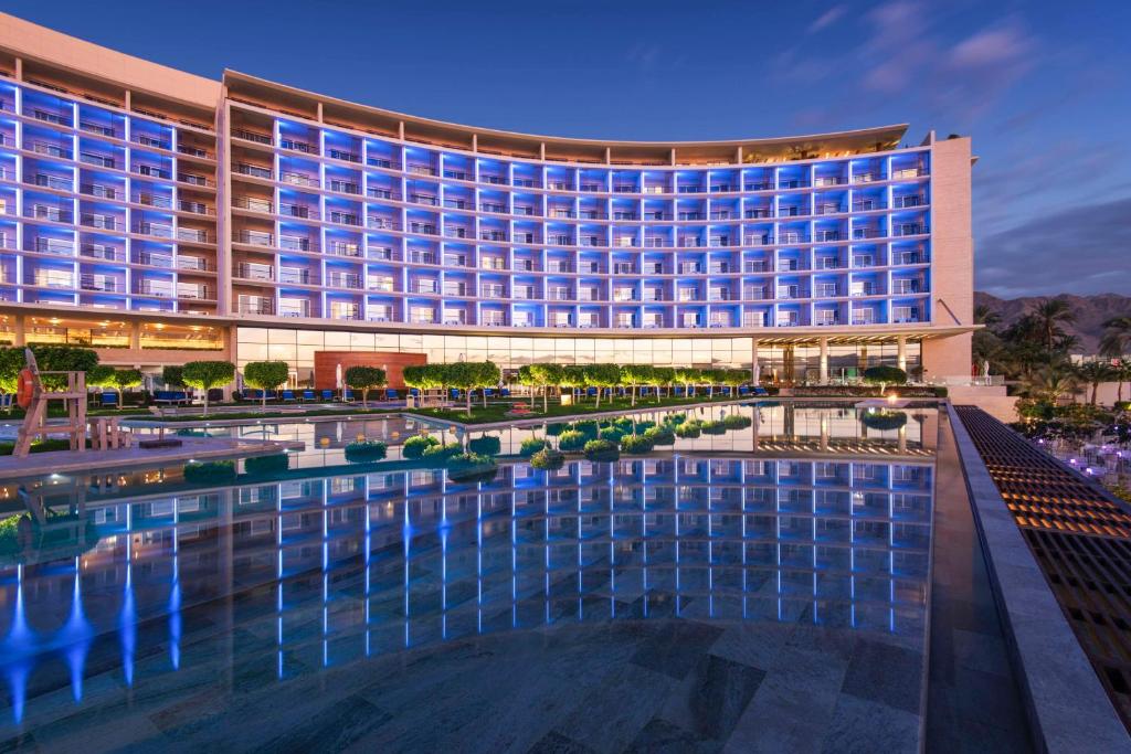 ein Hotel mit einem Pool vor einem Gebäude in der Unterkunft Kempinski Hotel Aqaba in Aqaba