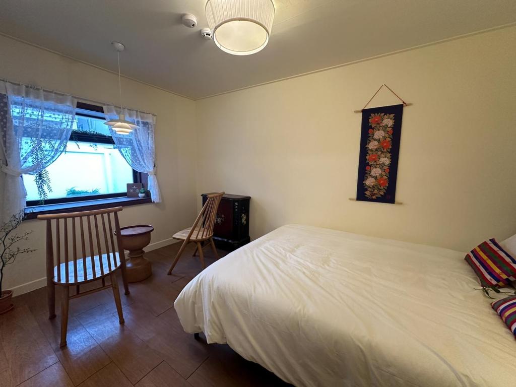 a bedroom with a bed and a chair and a window at Yunseul- Garden House in the City with Korean Beauty in Seoul