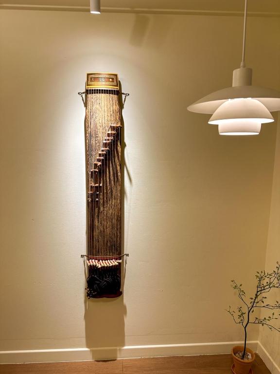 a guitar on the wall in a room with a light at Yunseul- Garden House in the City with Korean Beauty in Seoul