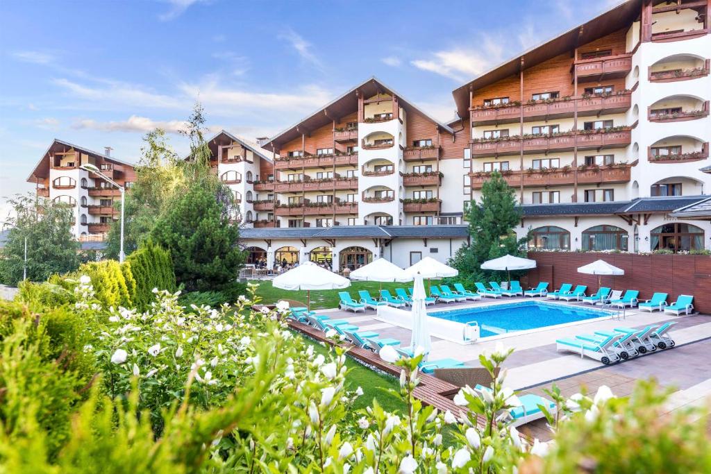a hotel with a pool and chairs and a building at Kempinski Hotel Grand Arena Bansko in Bansko