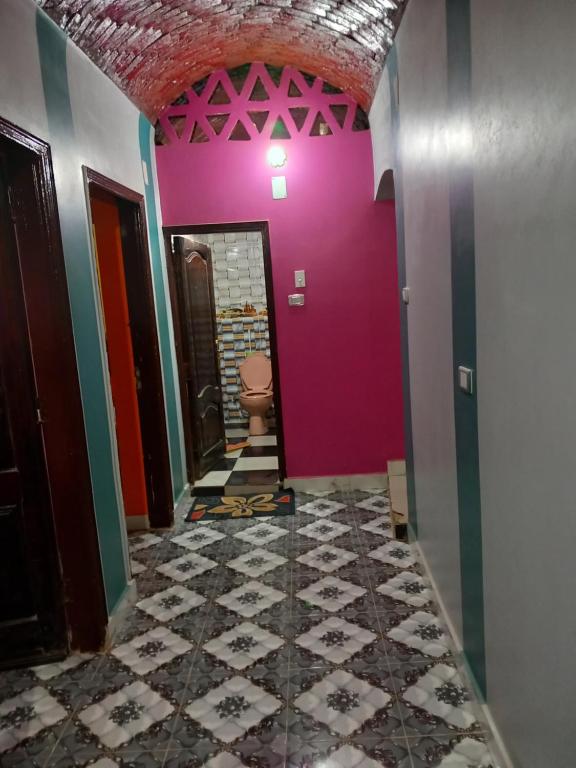 a hallway with a pink wall and a toilet at Noupian mother in Aswan