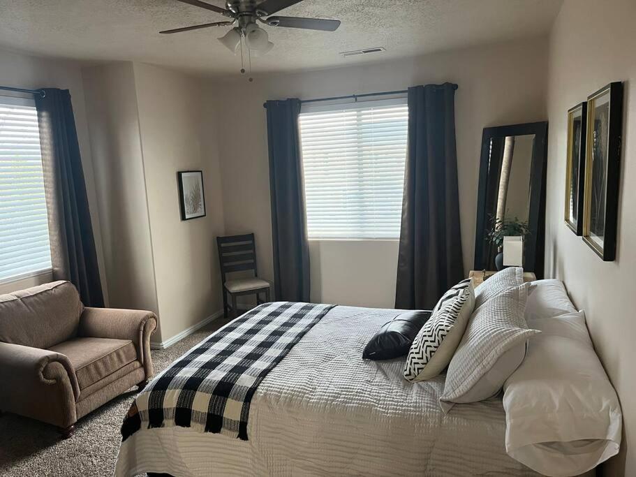 a bedroom with a bed and a chair and windows at Cozy Springs in Mesquite