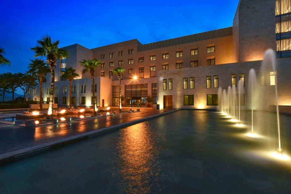 a building with a fountain in front of a building at Kempinski Hotel Ishtar Dead Sea in Sowayma