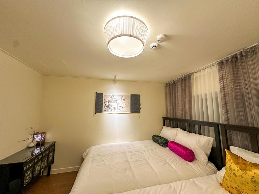a bedroom with a bed with white sheets and red pillows at Yunseul- Garden House in the City with Korean Beauty in Seoul