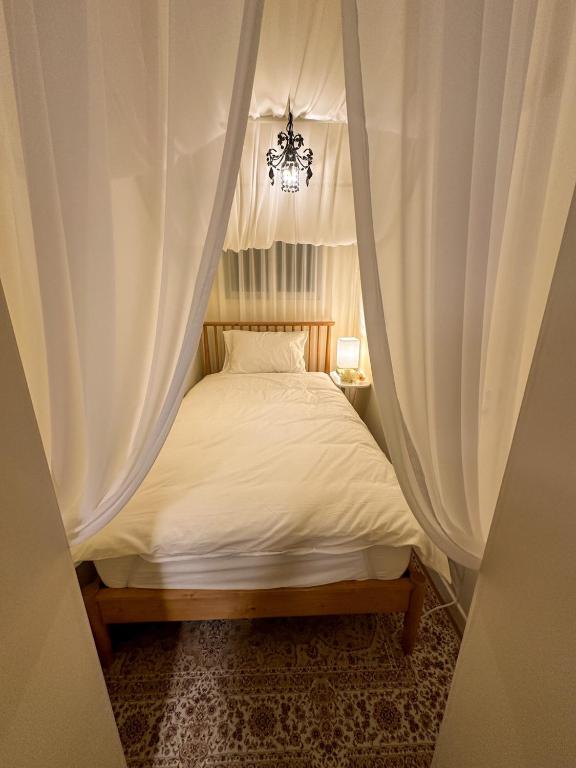 a bedroom with a bed with curtains and a chandelier at Yunseul- Garden House in the City with Korean Beauty in Seoul
