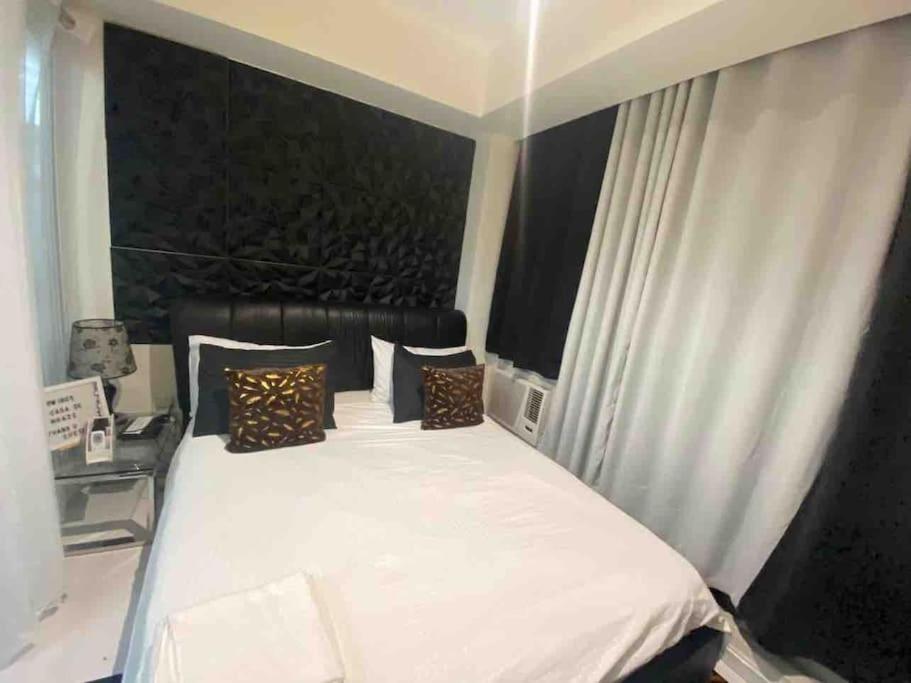 a bedroom with a large white bed with pillows at Azure skyview 1BR netflix karaoke ps3 Airport in Manila