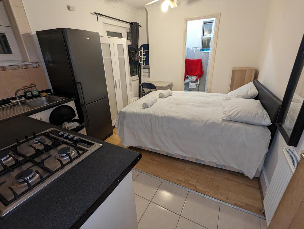 a bedroom with a bed and a kitchen with a stove at Stepney Green Self Contained Studio in London