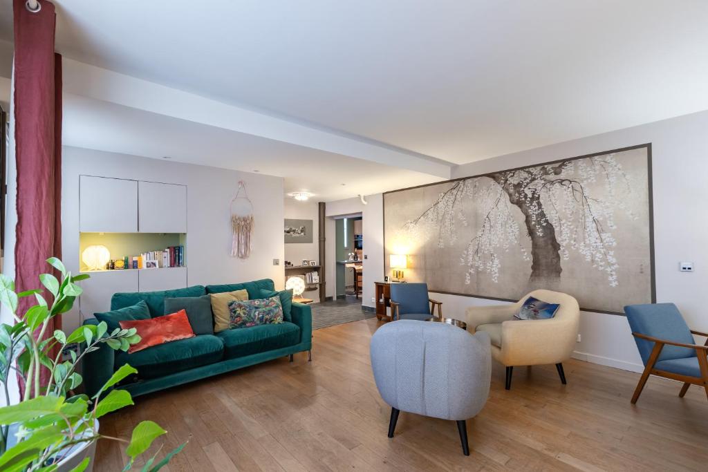 un salon avec un canapé vert et des chaises dans l'établissement Spacieux appartement Paris 17ème - Batignolles, à Paris