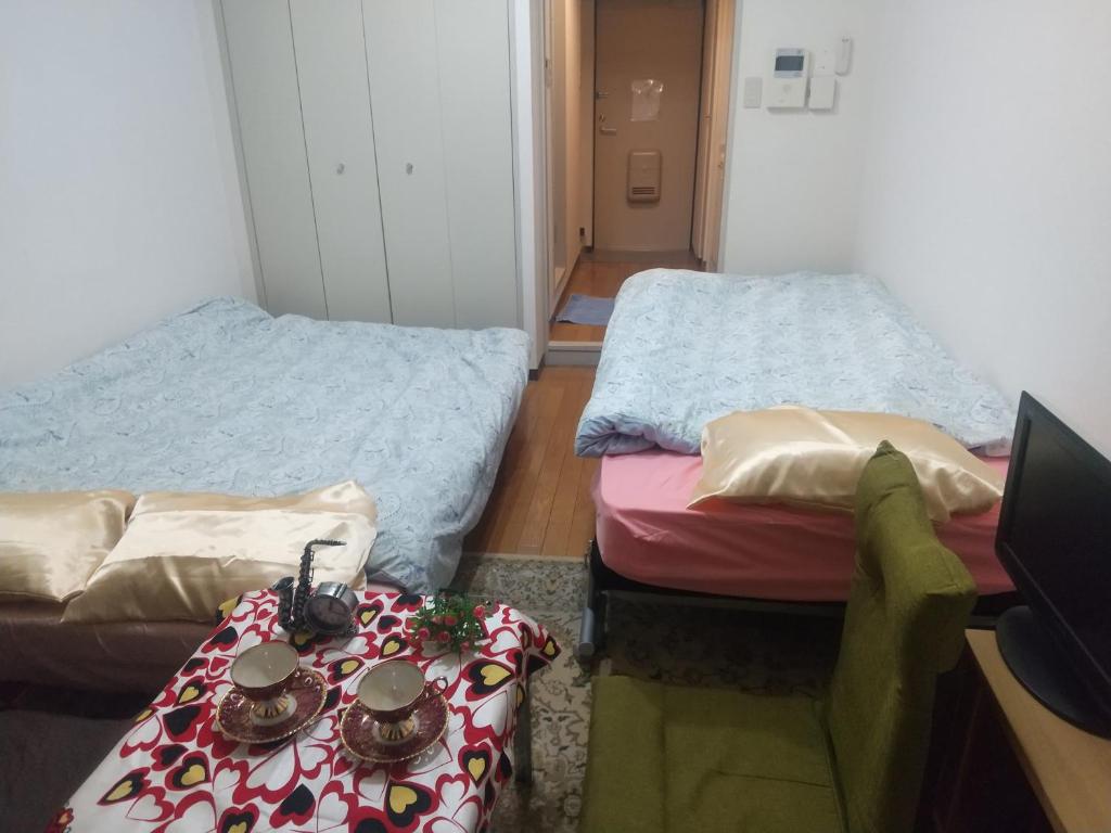 a room with two beds and a desk with a television at リリープロスパー泉 in Aoichō