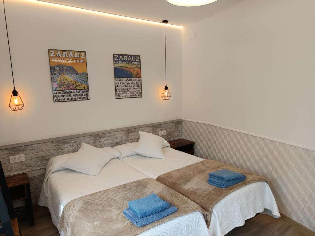 a bedroom with a bed with two blue towels on it at Kaixo Family in Zarautz