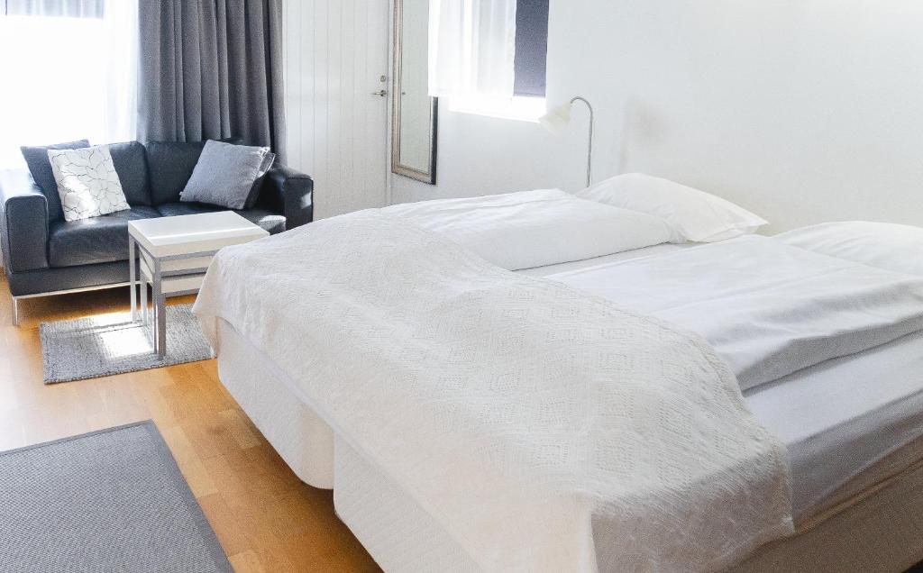 Un dormitorio blanco con 2 camas y una silla en Hótel Dalvík, en Dalvík