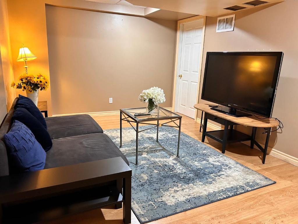 sala de estar con sofá y TV de pantalla plana en 温馨的两室一厅地下室套房独立卫浴5-6, en Bowmanville