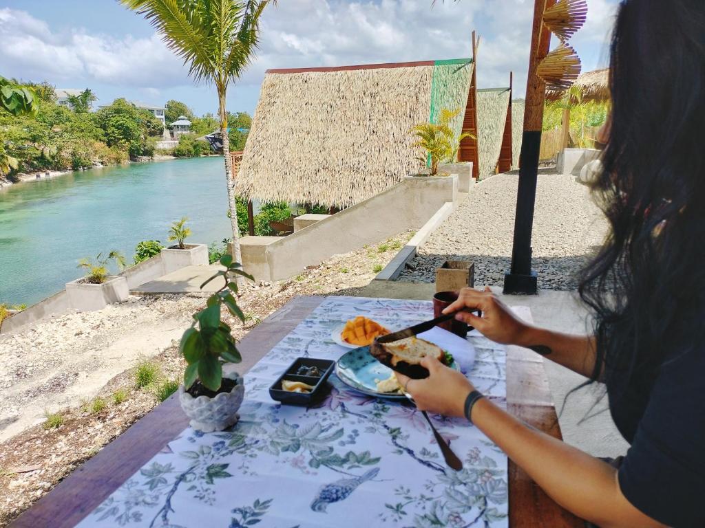 Una donna seduta a un tavolo con un piatto di cibo di Riu del Mar Hostel a Dauis