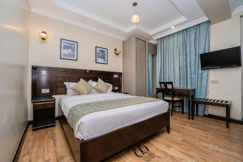 a bedroom with a bed and a desk and a television at Hemak Suites in Nairobi