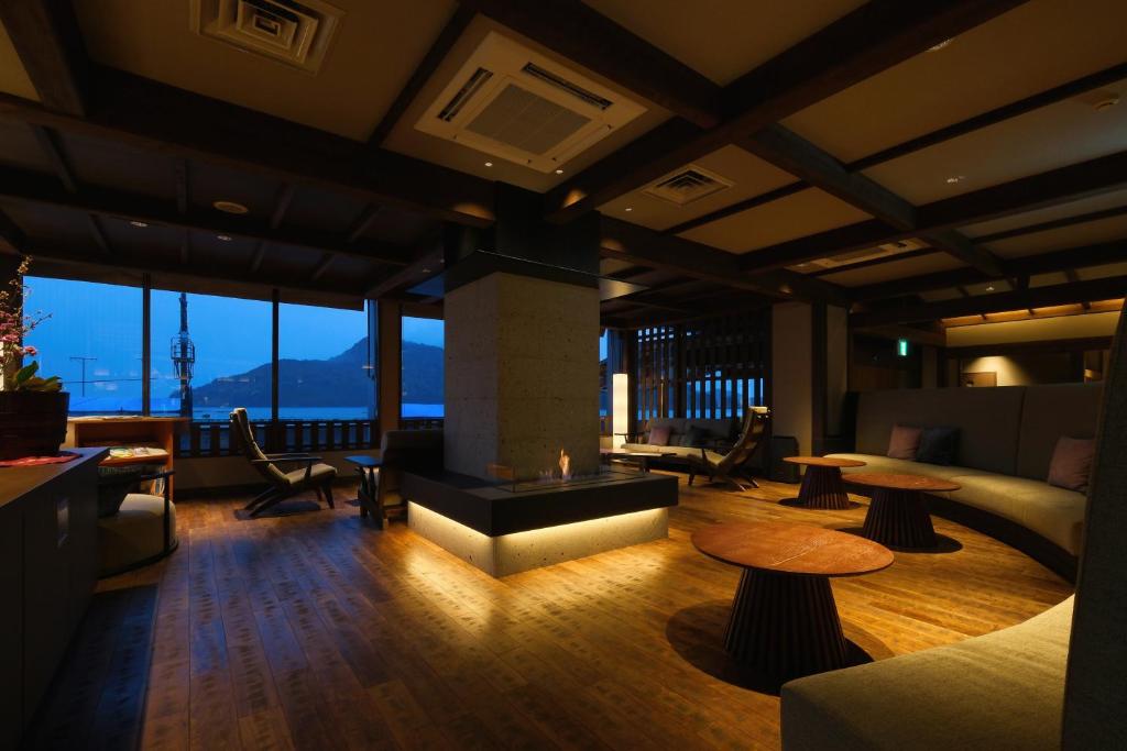a living room with a fireplace and tables and windows at Keishokan Sazanamitei in Fukuyama