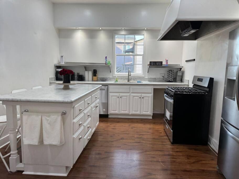 uma cozinha com armários brancos e um frigorífico preto em Spacious Downtown Home SJ em San José