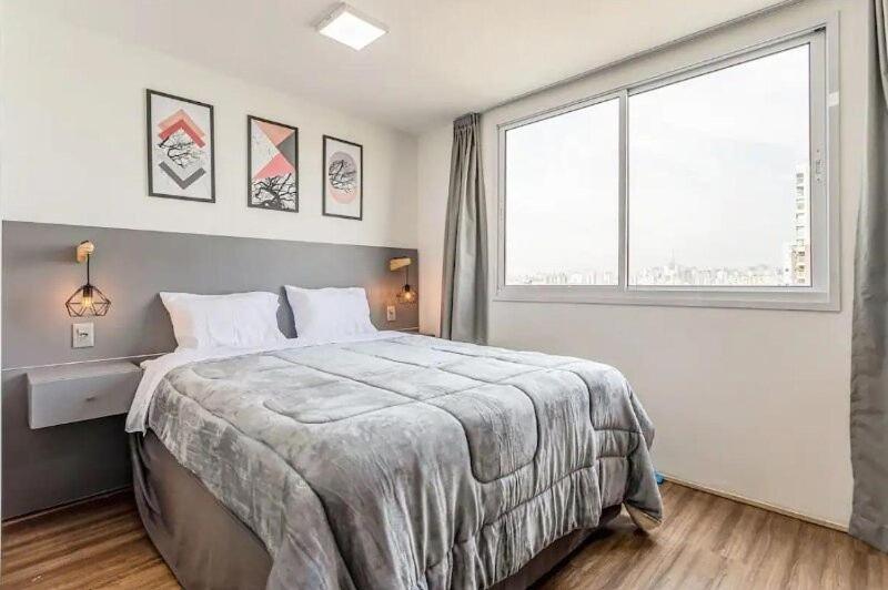 1 dormitorio con cama grande y ventana grande en Fantástico Studio no Brás com Piscina/Metrô Brás, en São Paulo