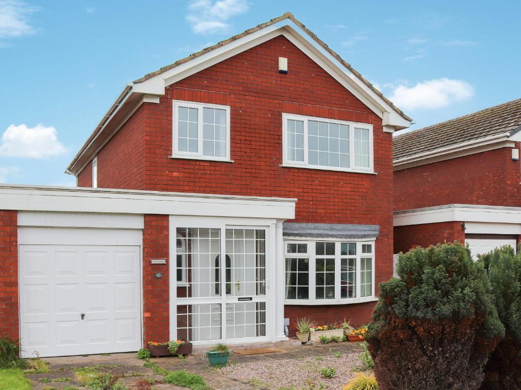 a red brick house with white garage doors at The Moorings in Rhyl