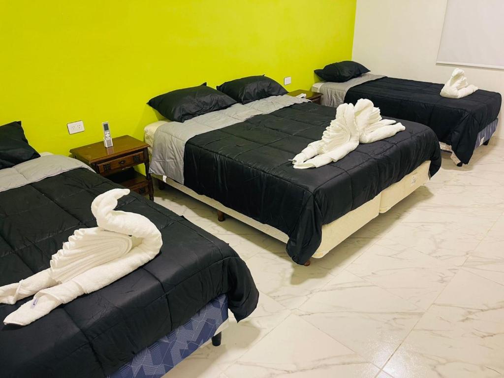 Tres camas en una habitación con toallas blancas. en departamentos Santino en Tinogasta