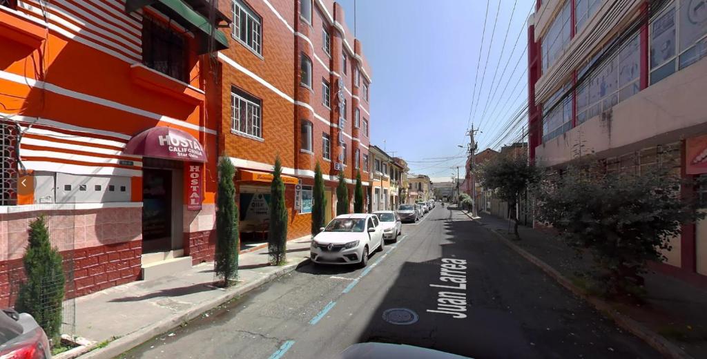 a street with cars parked on the side of a building at HOSTAL CALIFORNIA STAR QUITO in Quito