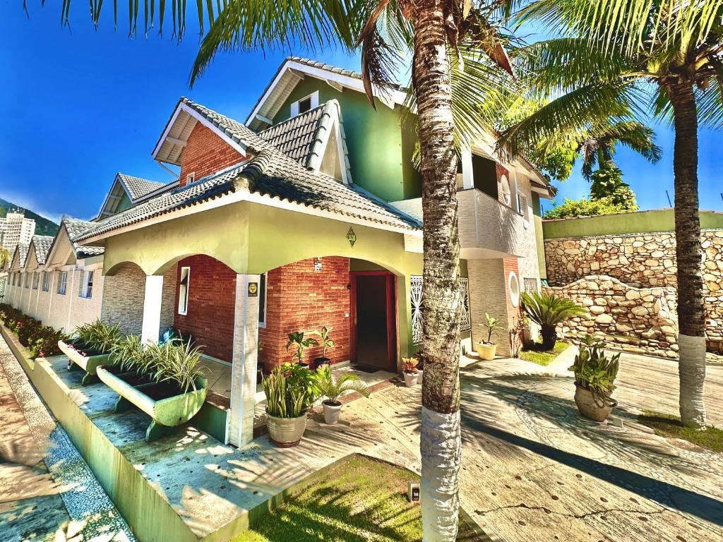 a house with palm trees in front of it at Surfside Suites in Peruíbe