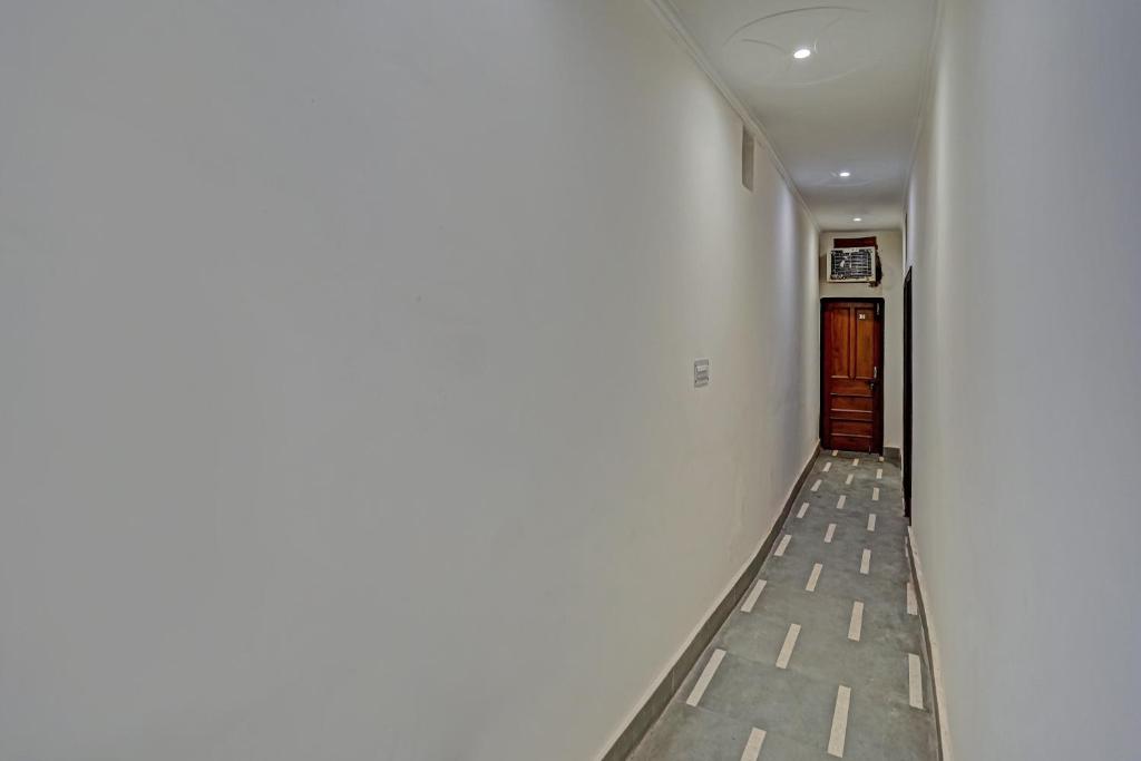 a hallway with a white wall and a door at OYO Hotel Jmd Residency in Shahdara