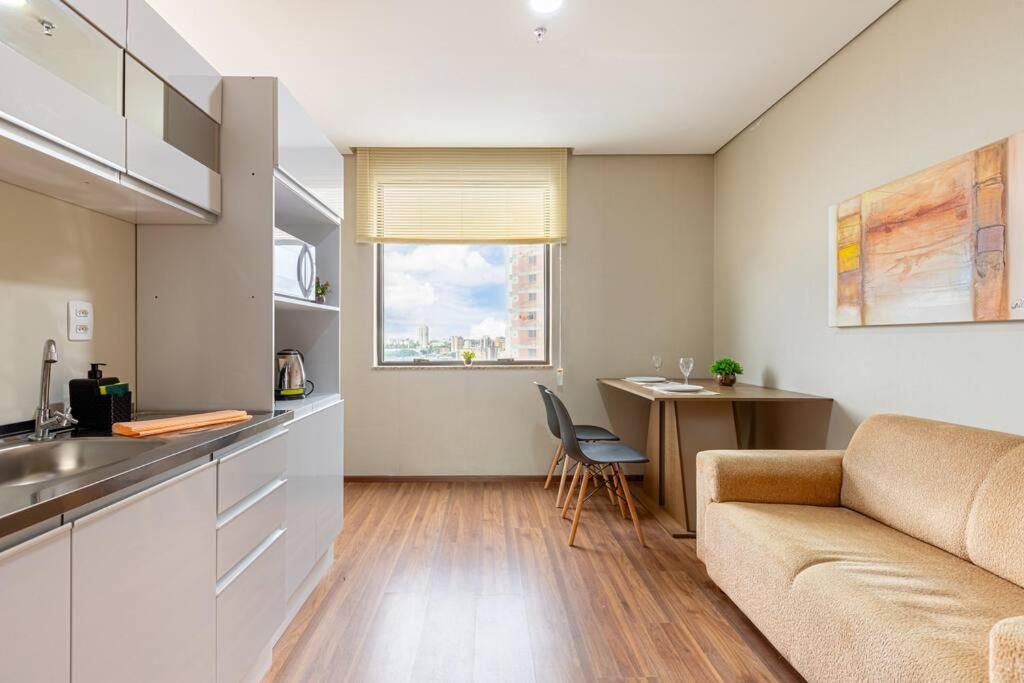 eine Küche und ein Wohnzimmer mit einem Sofa und einem Tisch in der Unterkunft Flat confortavel com cozinha, e piscina in Osasco