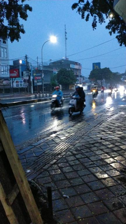 um grupo de motocicletas dirigindo por uma rua na chuva em Ifrazim home peninggilan em Bulak
