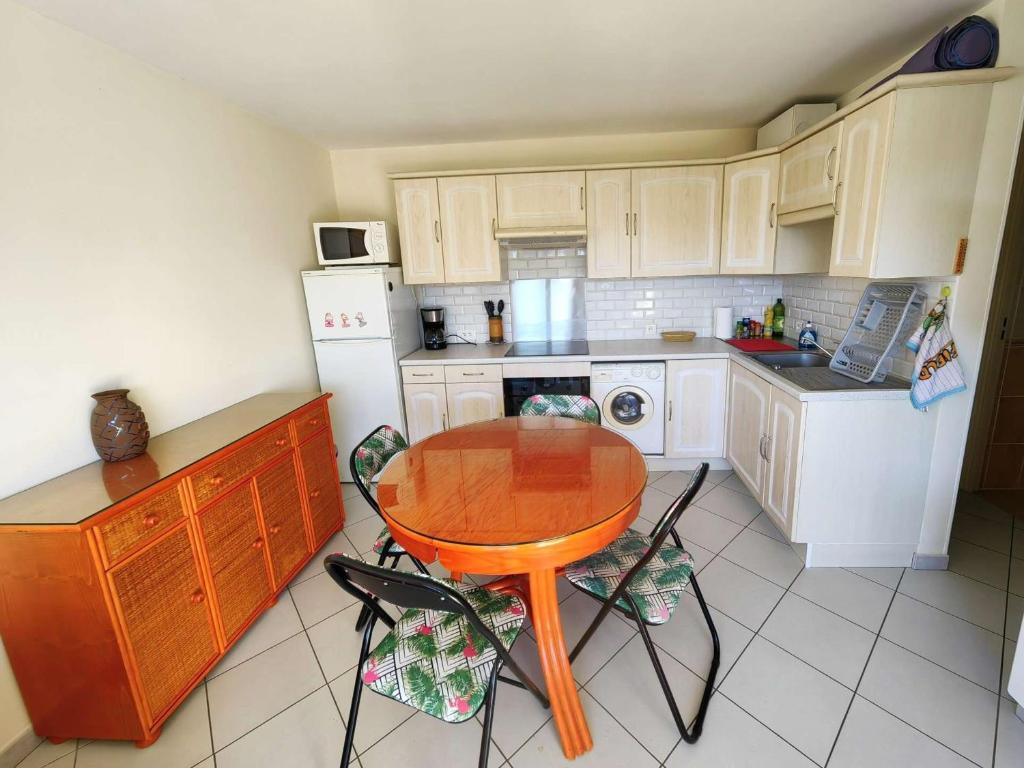 une cuisine avec une table en bois et une table et des chaises dans l'établissement Appartement T2 pour 4 pers, avec piscine, tennis, parking et terrasse, à 400m de la plage - FR-1-607-190, au Cap d'Agde