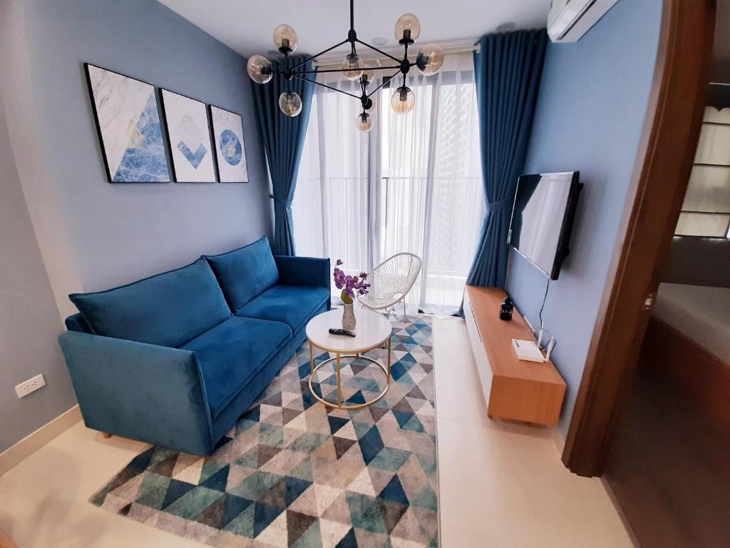 sala de estar con sofá azul y TV en Asahi Luxstay - FLC Green Home Pham Hung 2Br Apartment, en Hanói