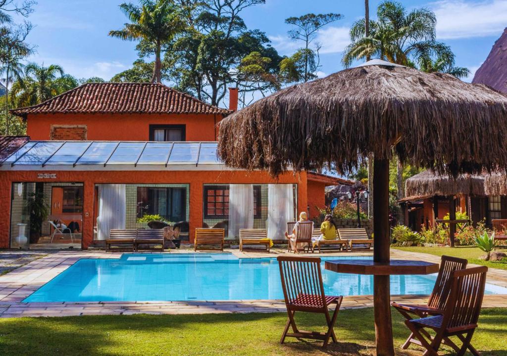 uma casa com piscina e guarda-chuva de palha em Kastel Pedra Bonita em Petrópolis