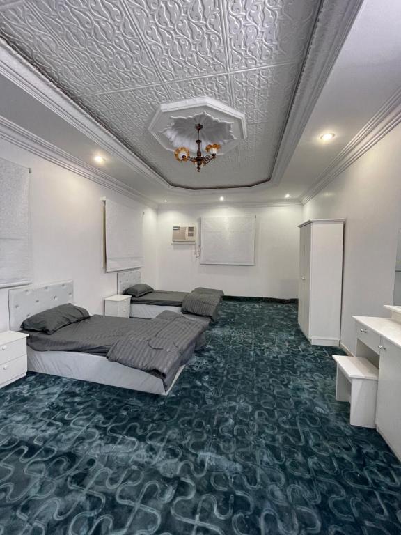 1 dormitorio con 2 camas y techo con lámpara de araña. en شقق نواف المفروشة, en Al Bad‘