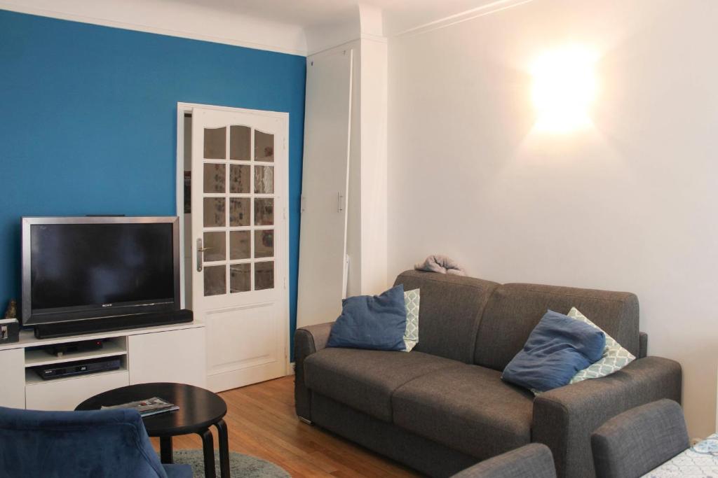 un salon avec un canapé et une télévision dans l'établissement Spacious family nest facing Square des Épinette, à Paris