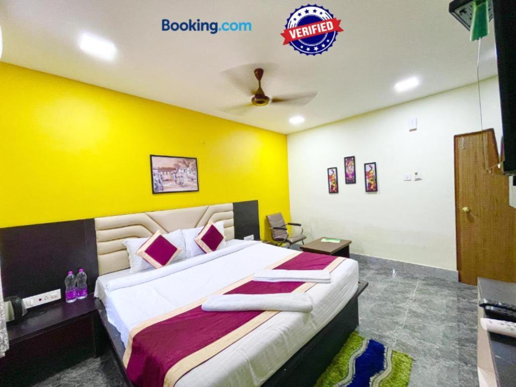 - une chambre avec un grand lit et un mur jaune dans l'établissement Hotel Corel Suit Swimming Pool Hotel, à Purî