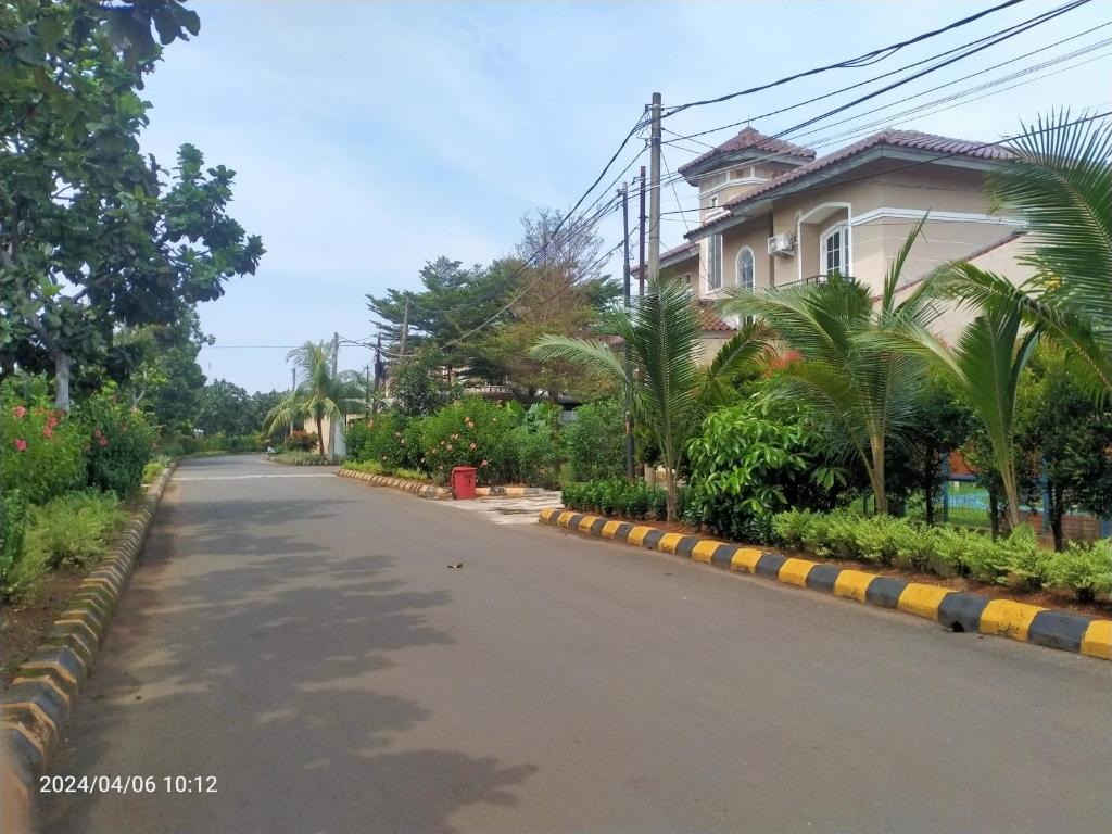 an empty street with a house and palm trees at Ifrazim home palem ganda asri 2 in Meruya-hilir