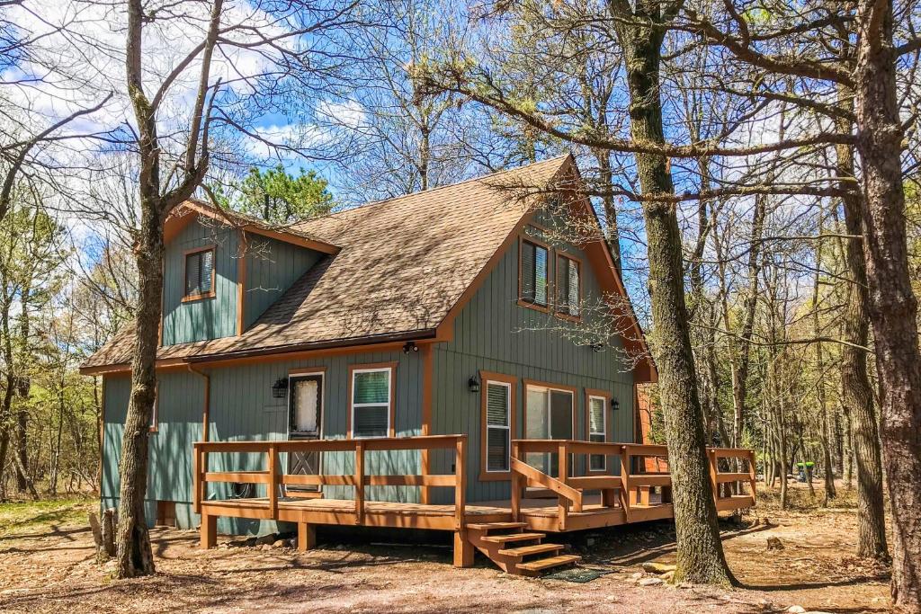 una casa verde con porche en el bosque en The Fox Chalet AvantStay Private Hot Tub Deck en Albrightsville