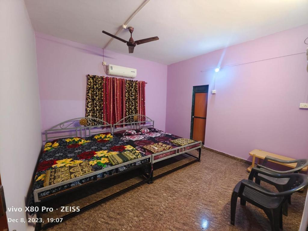 a bedroom with a bed and a window and chairs at Mahalaxmi home stay tarkarli devbag beach in Bhogwe