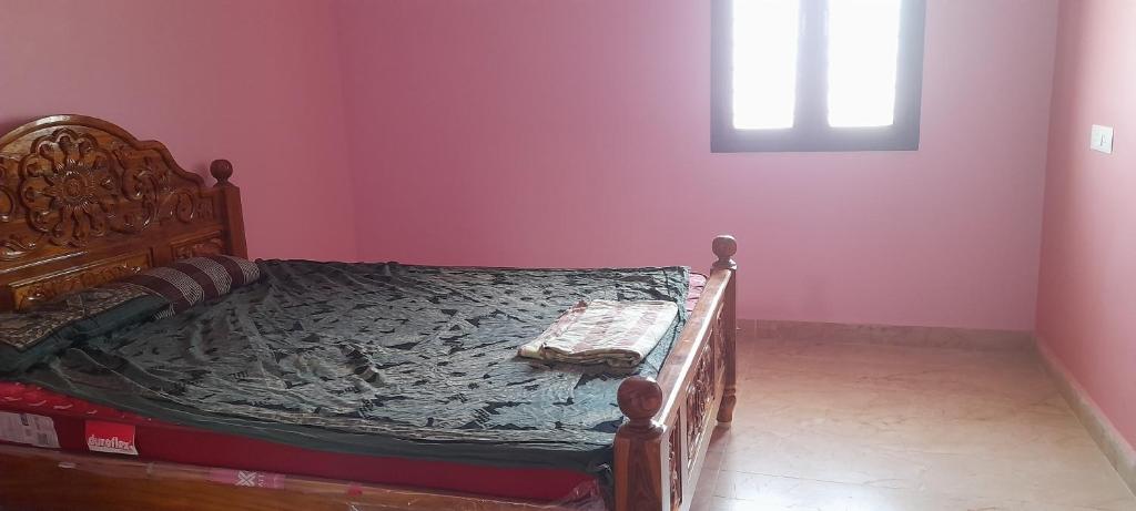 a bedroom with a wooden bed in a pink wall at Priya home in Tiruvannāmalai