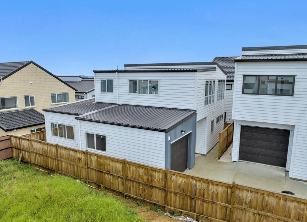 eine Reihe weißer Häuser hinter einem Holzzaun in der Unterkunft Private Ensuite for singles or couples in Auckland