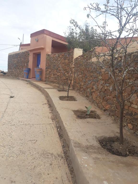 eine Steinmauer mit zwei Bäumen neben einem Bürgersteig in der Unterkunft maison d hote timentour in Tiguissas