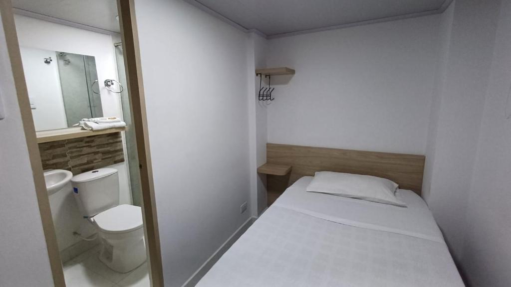 Habitación pequeña con cama y aseo en Hotel Adel en Manizales
