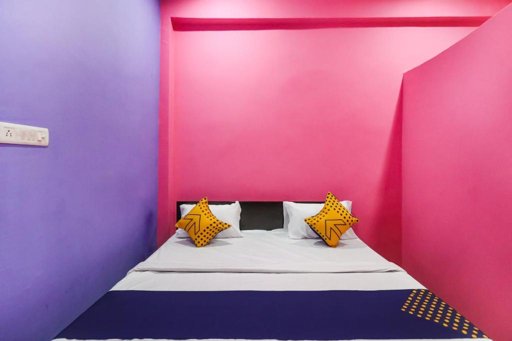 łóżko w pokoju z różowymi i fioletowymi ścianami w obiekcie OYO 78880 Rajdhani Hotel w mieście Kākori