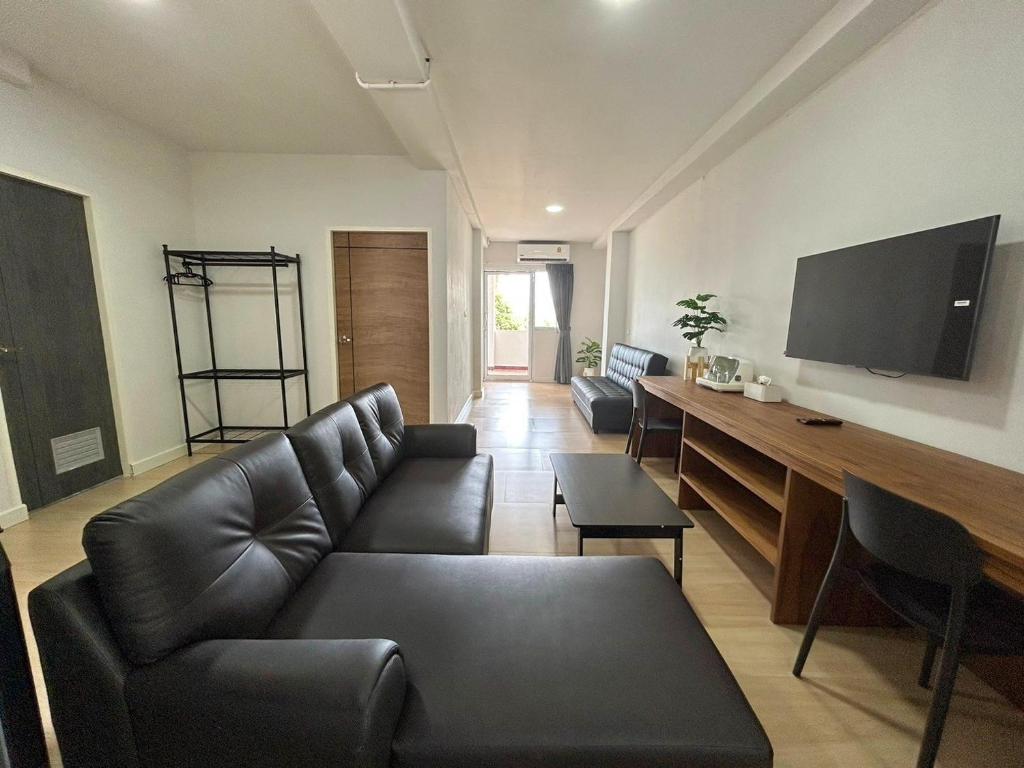 a living room with a black couch and a flat screen tv at idyllic apartment in Chaweng