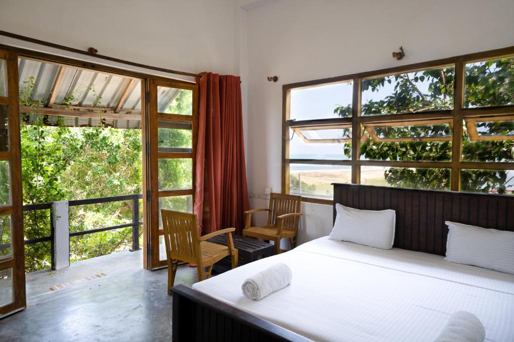 sypialnia z łóżkiem i dużymi oknami w obiekcie Rise & Set Arugam bay w mieście Arugam Bay