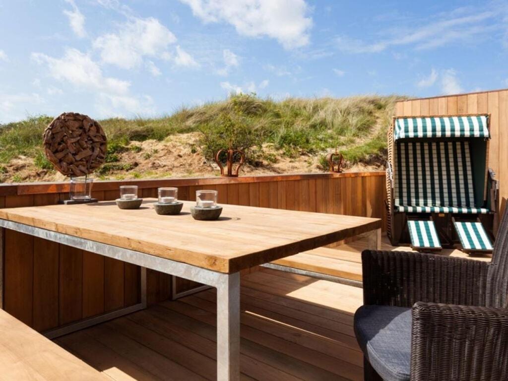 einen Holztisch auf einer Terrasse mit 2 Stühlen in der Unterkunft Reethuus Süd Modern retreat in Juist