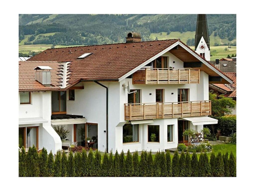 a large white house with a wooden balcony at 1 Porzig Modern retreat in Fischen