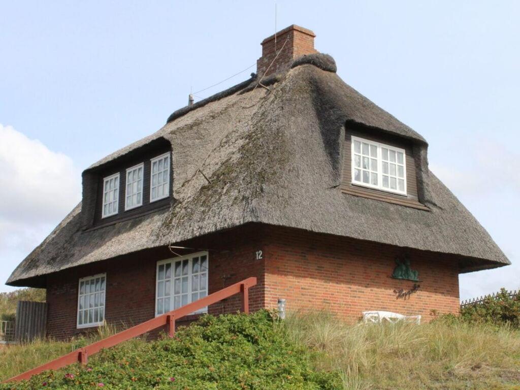 a house with a thatched roof on a field at Haus Hoppel - FeWo ground floor in Rantum